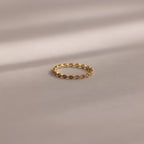 A delicate Dainty Marquise Birthstone Ring in Amethyst (February) rests on a soft beige surface, softly illuminated.