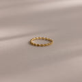 The Dainty Marquise Peridot Ring, featuring a delicate gold Art Deco-inspired twisted design, rests on a soft, neutral surface.