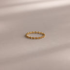 The Dainty Marquise Topaz Ring, featuring a repeating marquise pattern, rests on a smooth, neutral surface with soft shadows.