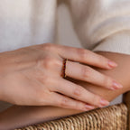 A hand wearing the Staggered Marquise Birthstone Ring rests on a woven surface.