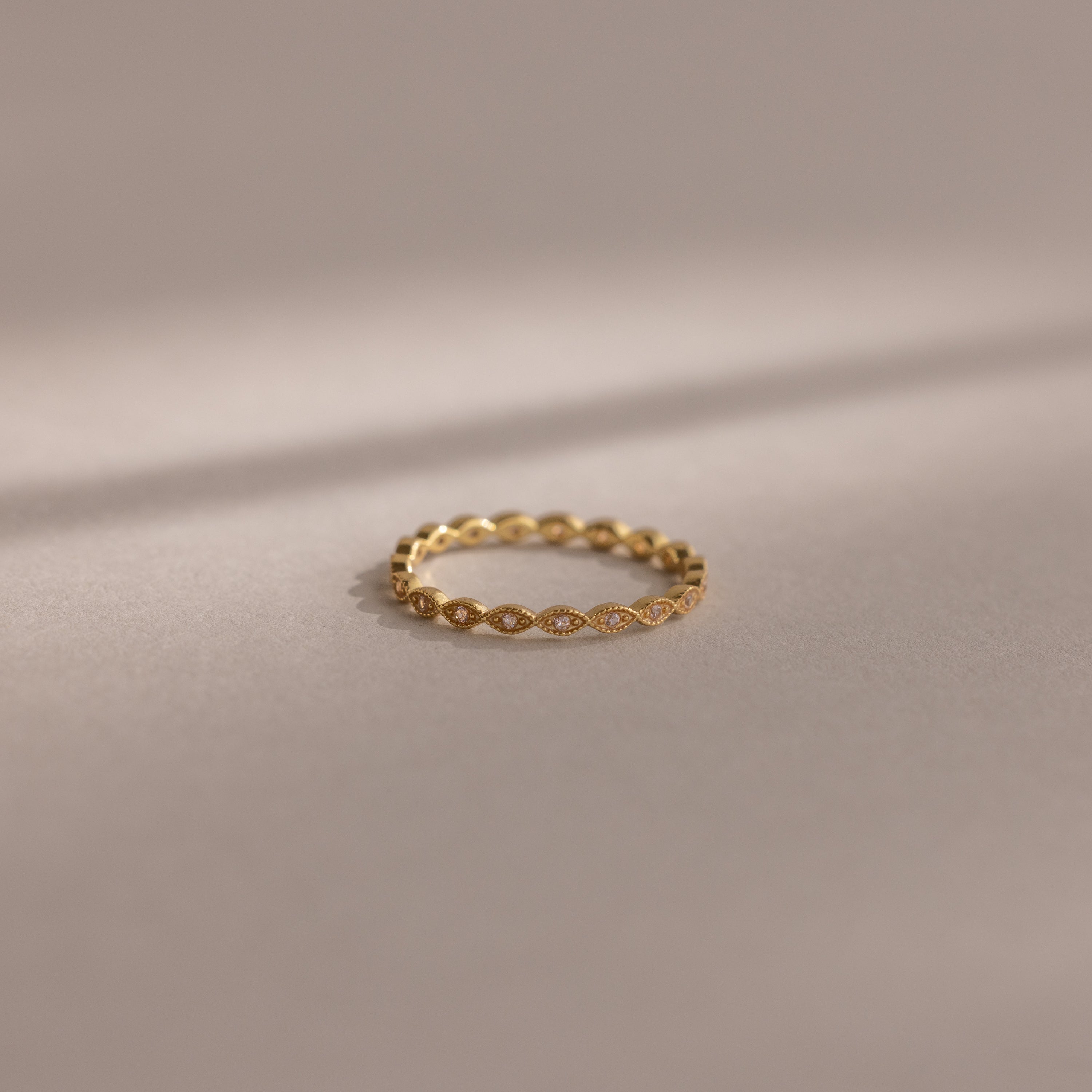 The Dainty Marquise Pink Tourmaline Ring, featuring a delicate gold design and marquise pattern, is showcased on a soft neutral background under gentle lighting.