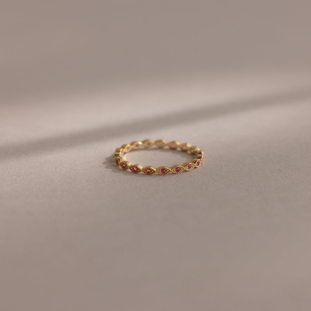 The Dainty Marquise Ruby Ring, featuring delicate gold and small red gemstones, is displayed on a soft, neutral background.