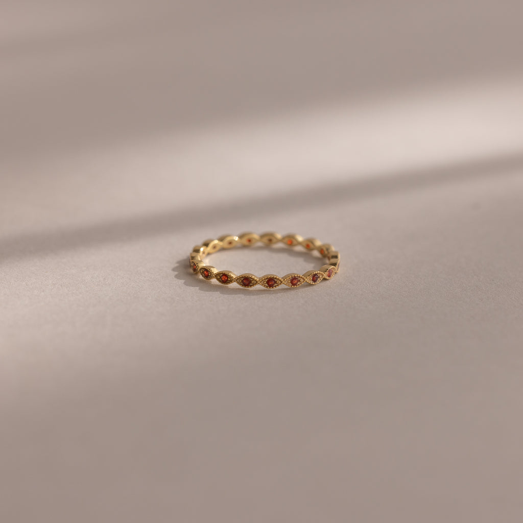 A Dainty Marquise Birthstone Ring in Garnet (January) rests on a soft, neutral surface under gentle lighting.