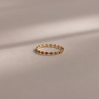 A Dainty Marquise Birthstone Ring in Garnet (January) rests on a soft, neutral surface under gentle lighting.