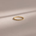 The Dainty Marquise Aquamarine Ring, featuring a delicate gold setting and intricate twisted design, rests on a soft neutral background.