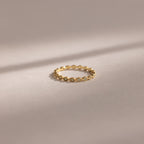 The Dainty Marquise Aquamarine Ring, featuring a delicate gold setting and intricate twisted design, rests on a soft neutral background.