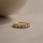 Diamond & Pearl Lace Ring featuring a sleek gold band with white pearls and round clear gemstones, elegantly displayed on a neutral beige surface.
