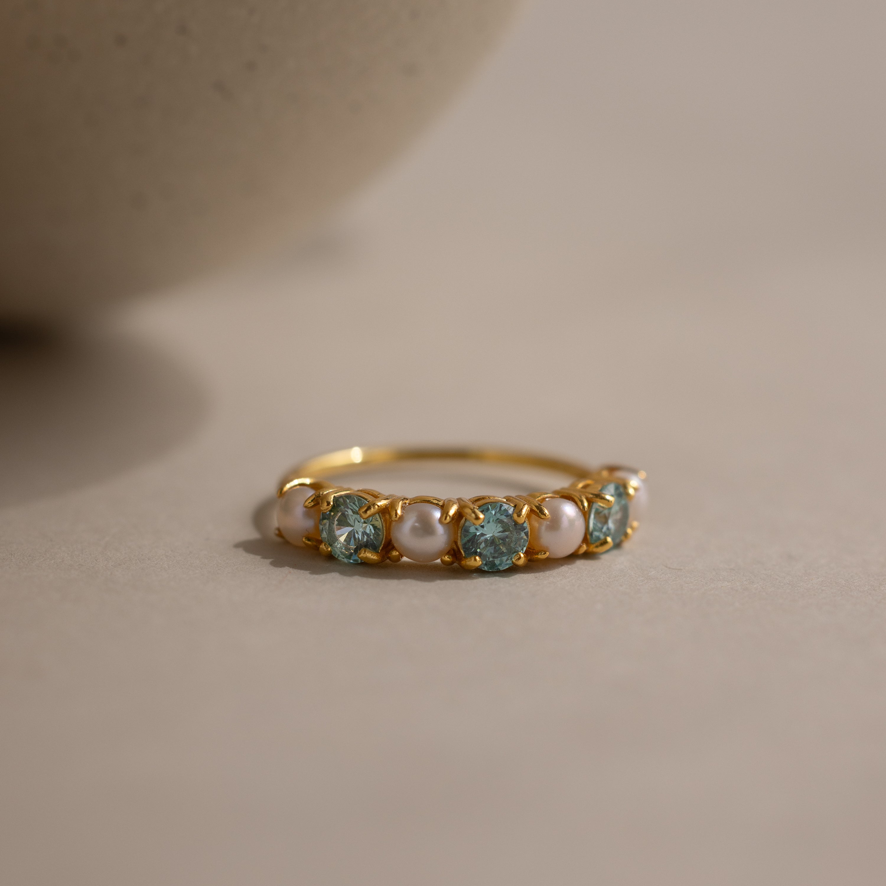 The Birthstone & Pearl Lace Ring in Aquamarine (March) features alternating blue gemstones and pearls on a gold band—an elegant choice for a unique birthstone or pearl ring.