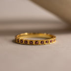 Art Deco Birthstone Eternity Ring in Amethyst (February birthstone) features small square purple gemstones set around the band, shown on a neutral background—an elegant vintage-inspired jewelry piece.