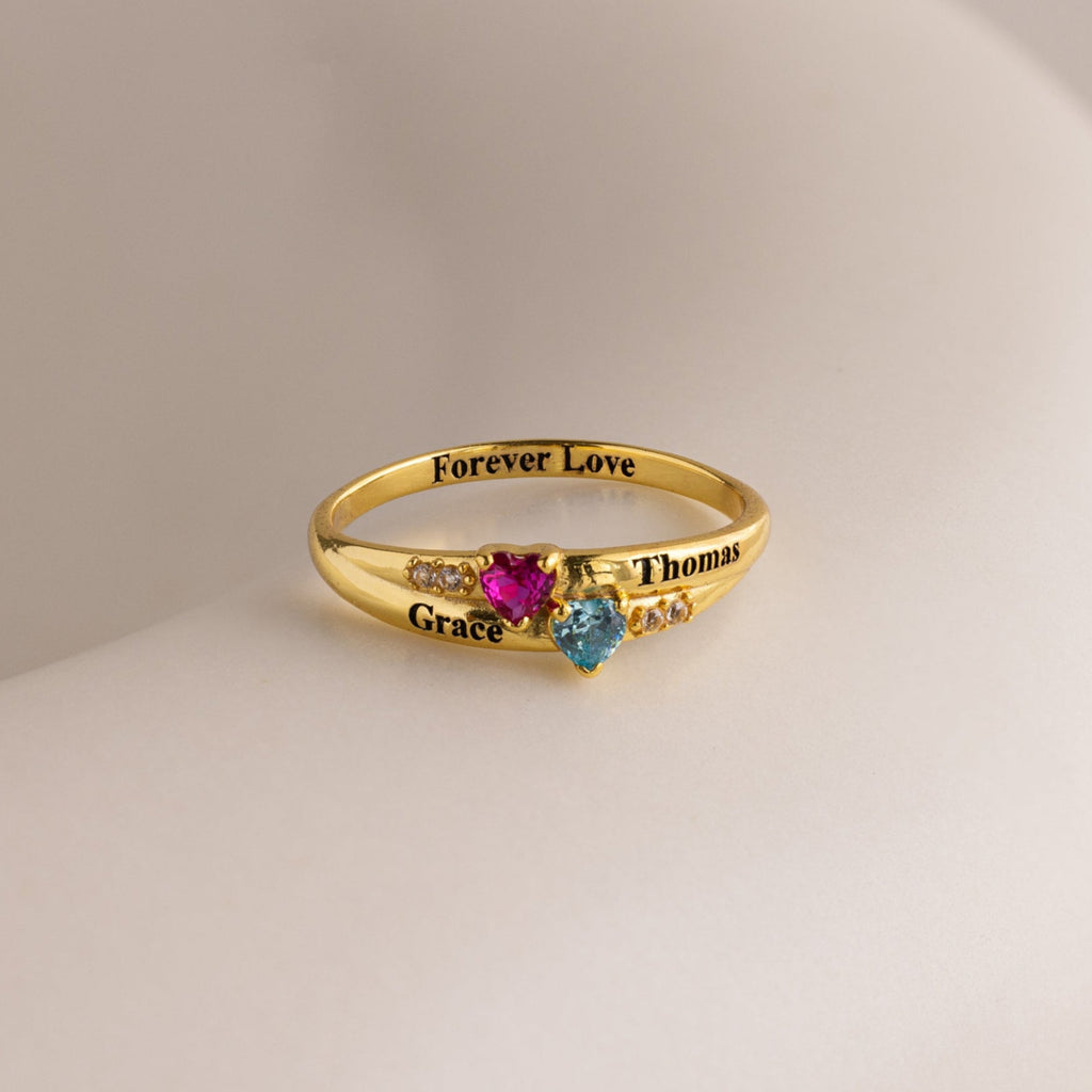 The Toi et Moi Interlocking Name Ring is a gold custom ring with two heart-shaped gems, engraved with Grace, Thomas, and Forever Love—perfect for symbolizing your special bond.