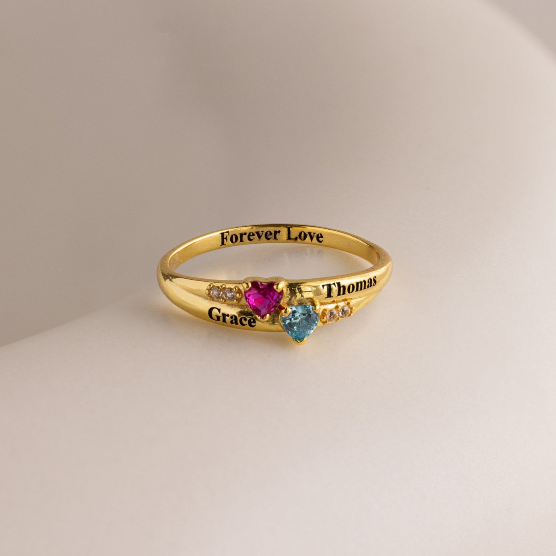 The Toi et Moi Interlocking Name Ring is a gold custom ring with two heart-shaped gems, engraved with Grace, Thomas, and Forever Love—perfect for symbolizing your special bond.