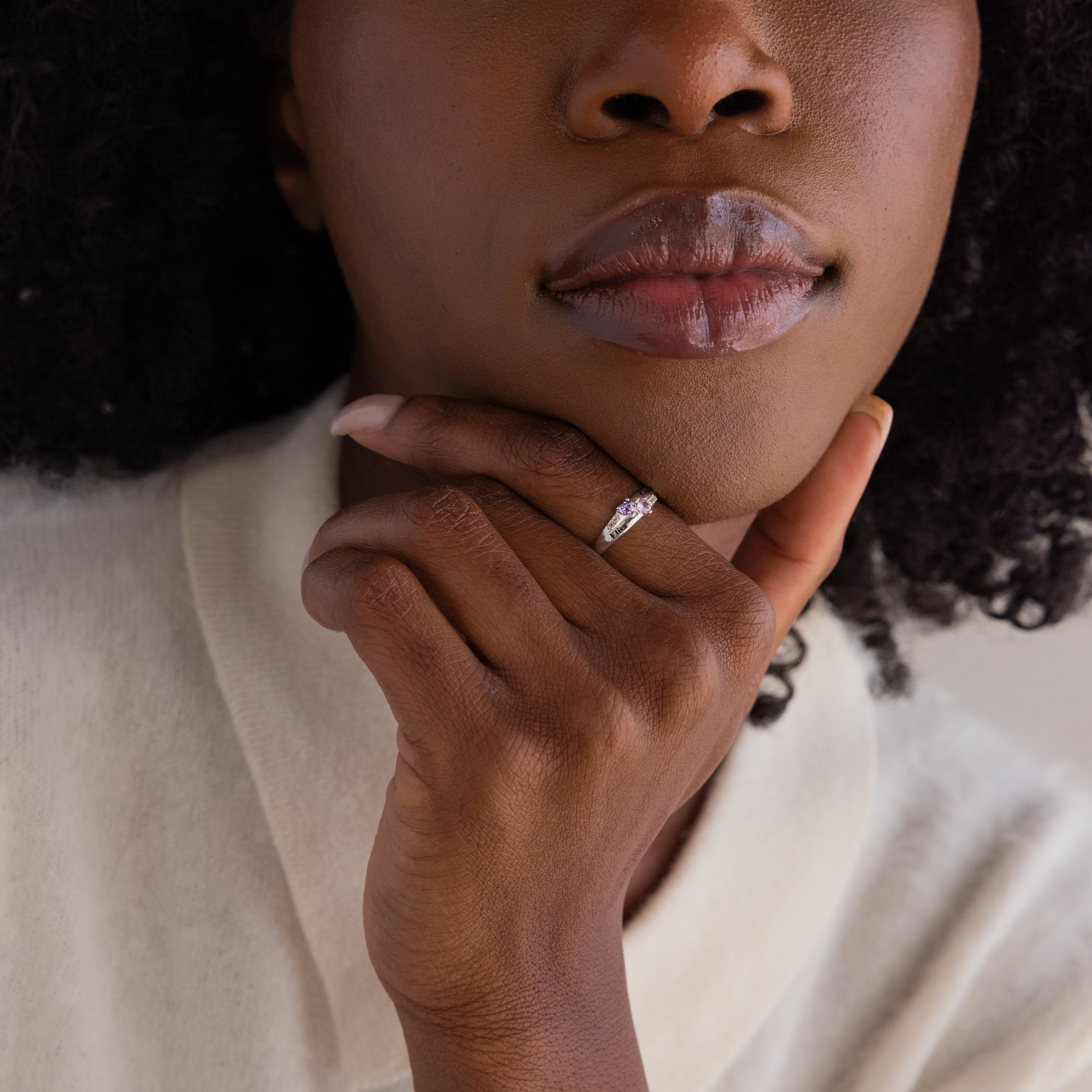 A woman rests her chin on her hand, displaying the Toi et Moi Interlocking Name Ring in Sterling Silver on her finger.