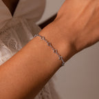 The Clover Station Bracelet in Silver, featuring geometric shapes, adds a delicate touch over a lace sleeve—perfect for those who love nature-inspired jewelry.