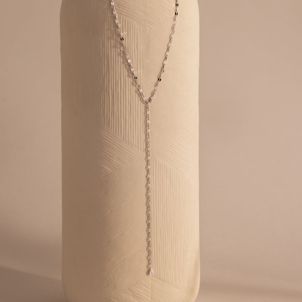 Silver dainty Sparkling Diamond Lariat Necklace with a delicate mirror chain design and two CZ diamond stones, displayed against a ceramic prop.
