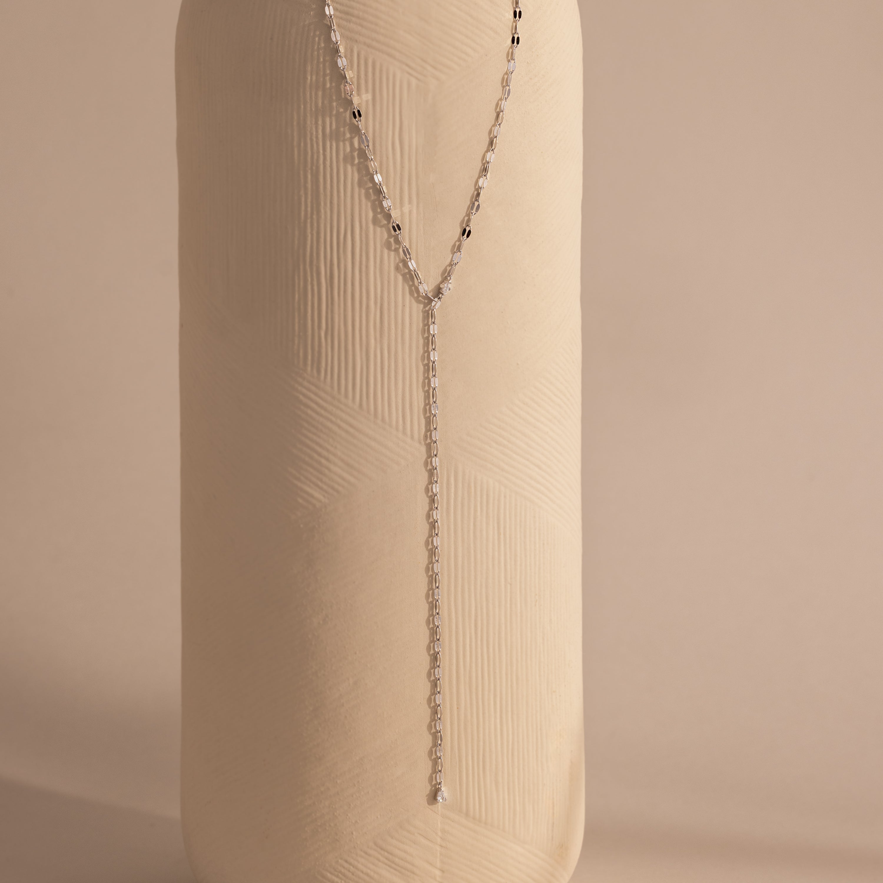 Silver dainty Sparkling Diamond Lariat Necklace with a delicate mirror chain design and two CZ diamond stones, displayed against a ceramic prop.