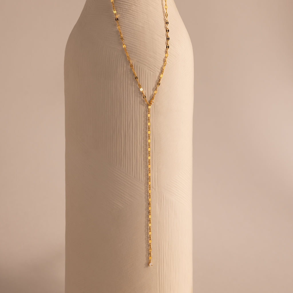 Gold dainty Sparkling Diamond Lariat Necklace with a delicate mirror chain design and two CZ diamond stones, displayed against a ceramic prop.