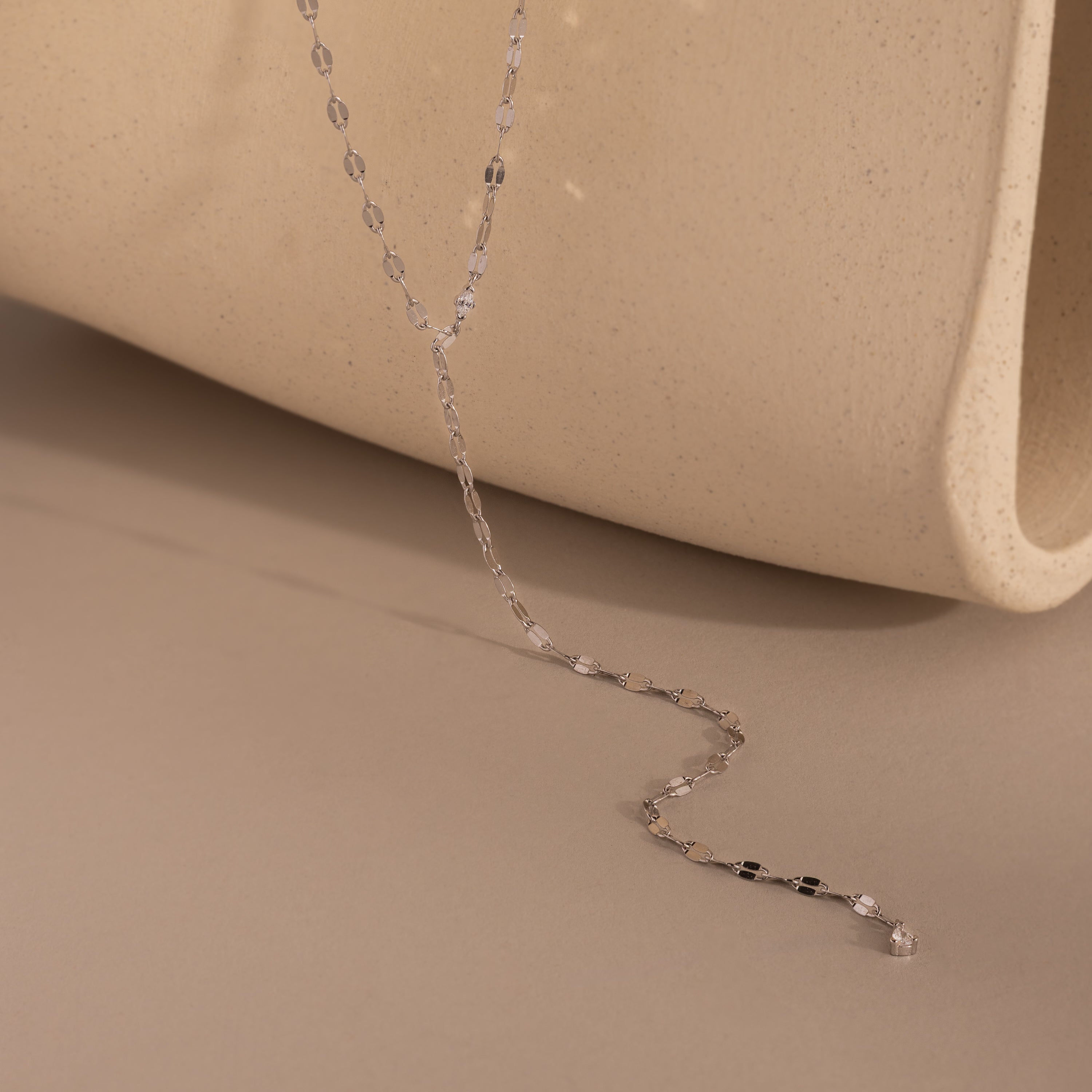 Silver dainty Sparkling Diamond Lariat Necklace with a delicate mirror chain design and two CZ diamond stones, displayed against a neutral-tone backdrop.