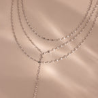 Close-up of a silver dainty Sparkling Layered Lariat Necklace, featuring 3 layers of mirror chain necklaces in varying lengths.