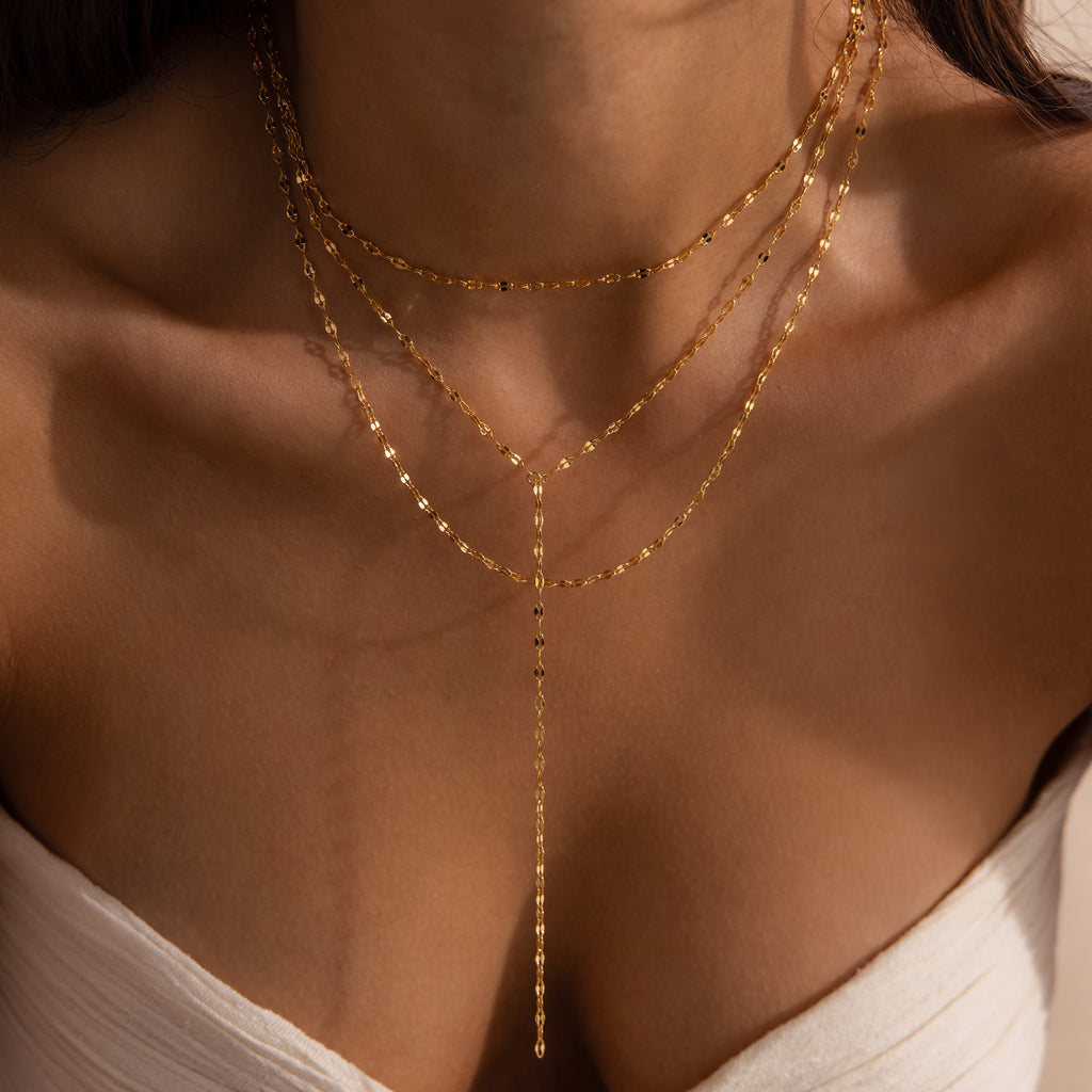 Model wearing a gold dainty Sparkling Layered Lariat Necklace, featuring 3 layers of mirror chain necklaces in varying lengths.