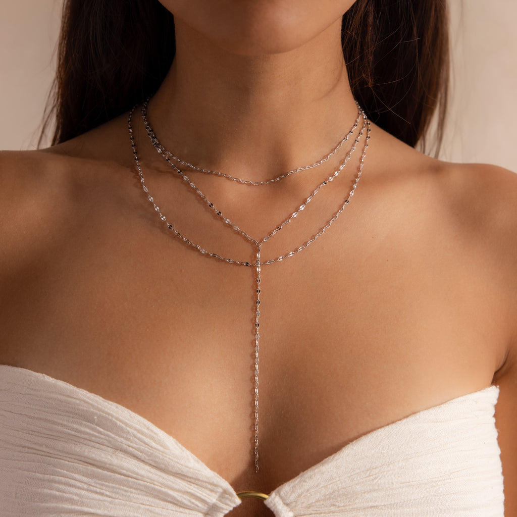 Model wearing a silver dainty Sparkling Layered Lariat Necklace, featuring 3 layers of mirror chain necklaces in varying lengths.