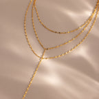 Close-up of a gold dainty Sparkling Layered Lariat Necklace, featuring 3 layers of mirror chain necklaces in varying lengths.