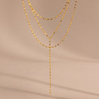 Close-up of a gold dainty Sparkling Layered Lariat Necklace, featuring 3 layers of mirror chain necklaces in varying lengths.