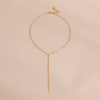 Gold dainty mirror chain lariat necklace displayed against an off-white surface.