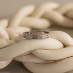 The Filigree Ring in Sterling Silver is displayed atop thick, intertwined ivory-colored ropes.