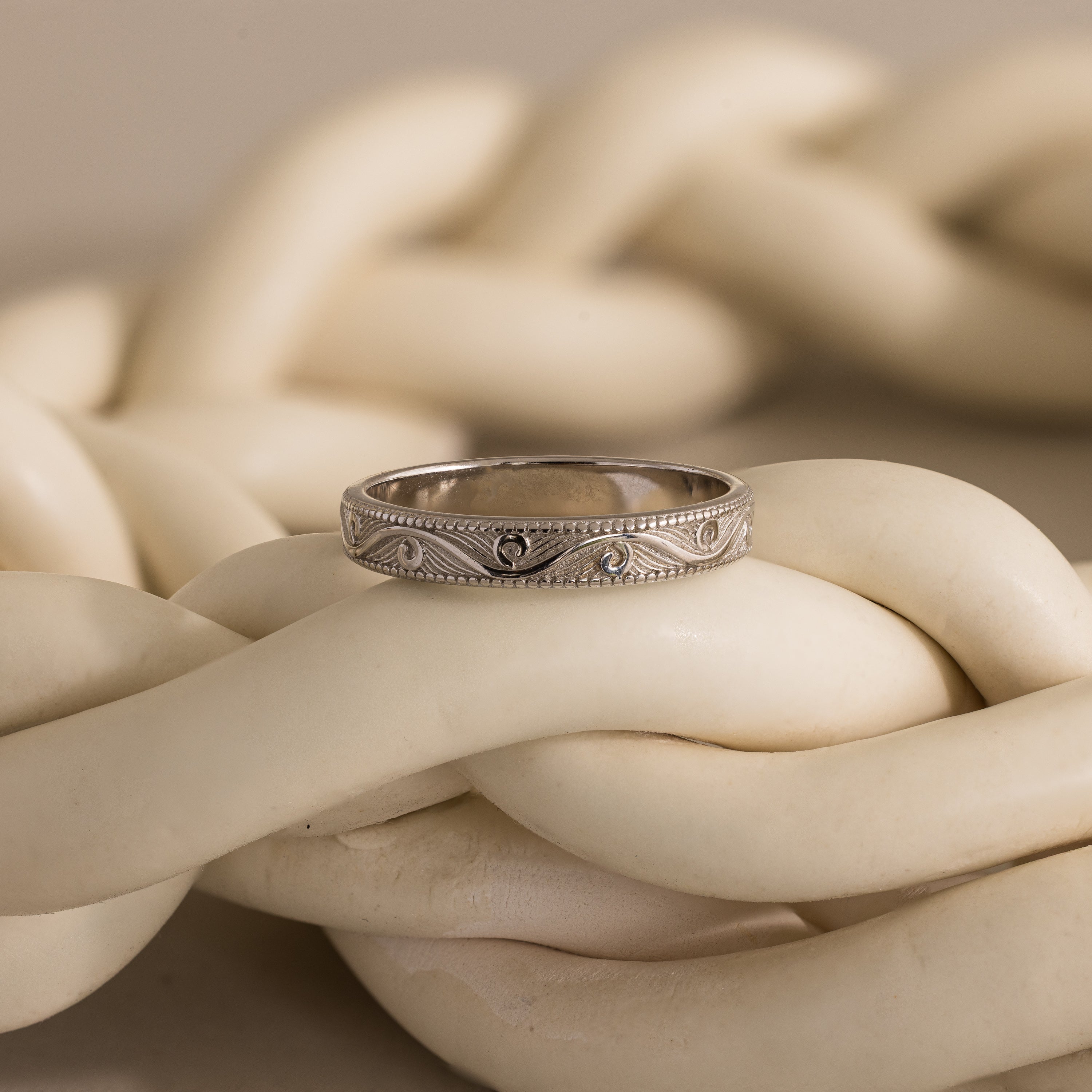 The Filigree Ring in Sterling Silver is displayed atop thick, intertwined ivory-colored ropes.