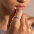 Someone wearing the Filigree Ring, a delicately engraved band featuring intricate details, holds their hand near their face.