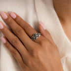 A hand with light pink nails wears three stacked silver rings, featuring the Emerald Stacking Ring Set in Sterling Silver with green and clear gemstones for a vintage, art deco look.