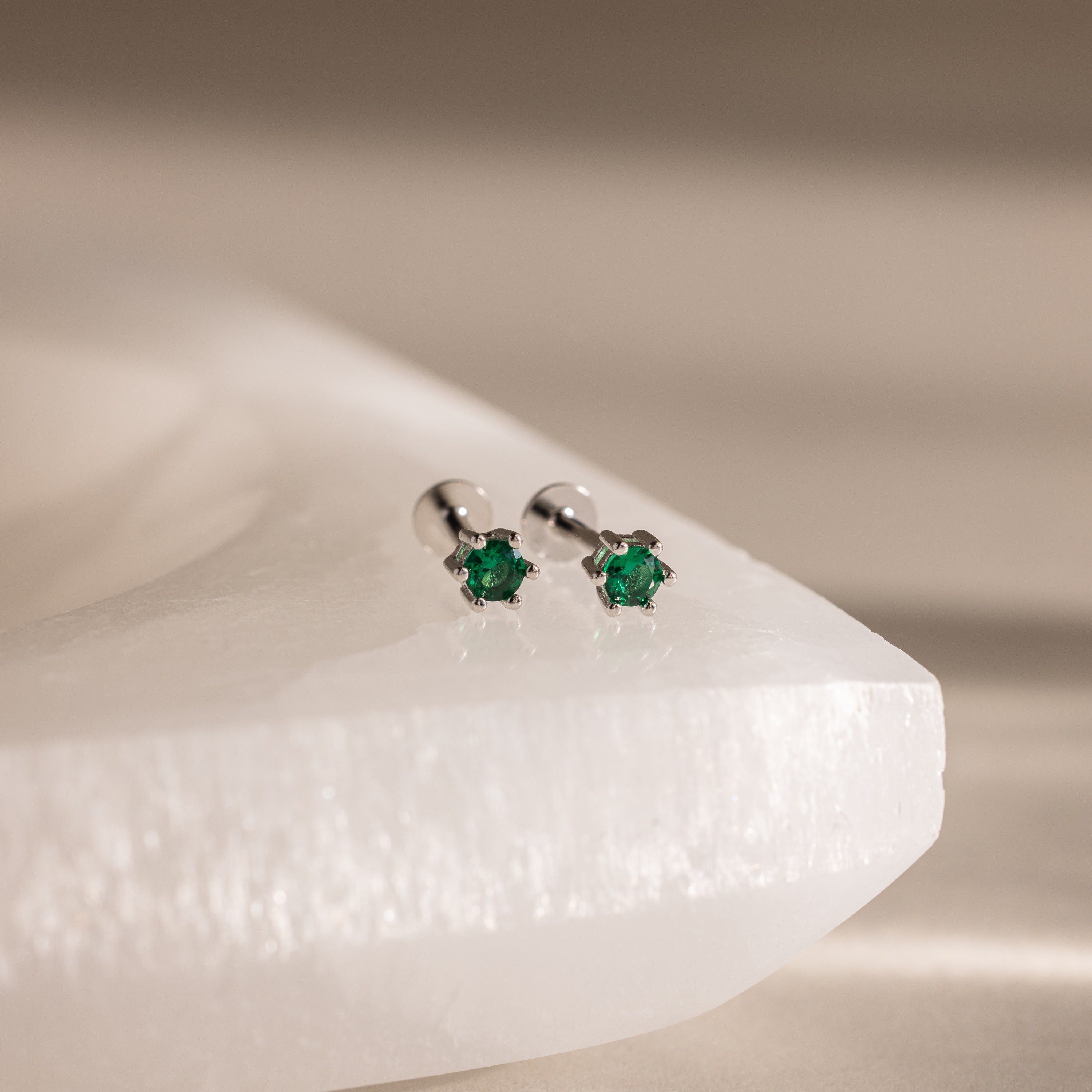 Emerald Flatback Studs with small green gemstones, elegantly displayed on a white textured surface—perfect personalized jewelry for a May birthstone gift.