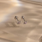 The Geometric Pink Tourmaline Flat Back Studs, featuring silver settings and geometric pink tourmaline gemstones, rest on a soft beige surface for an elegant birthstone earring look.