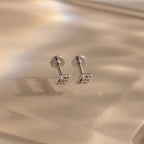 Pair of silver geometric flat back topaz stud earrings on a beige background