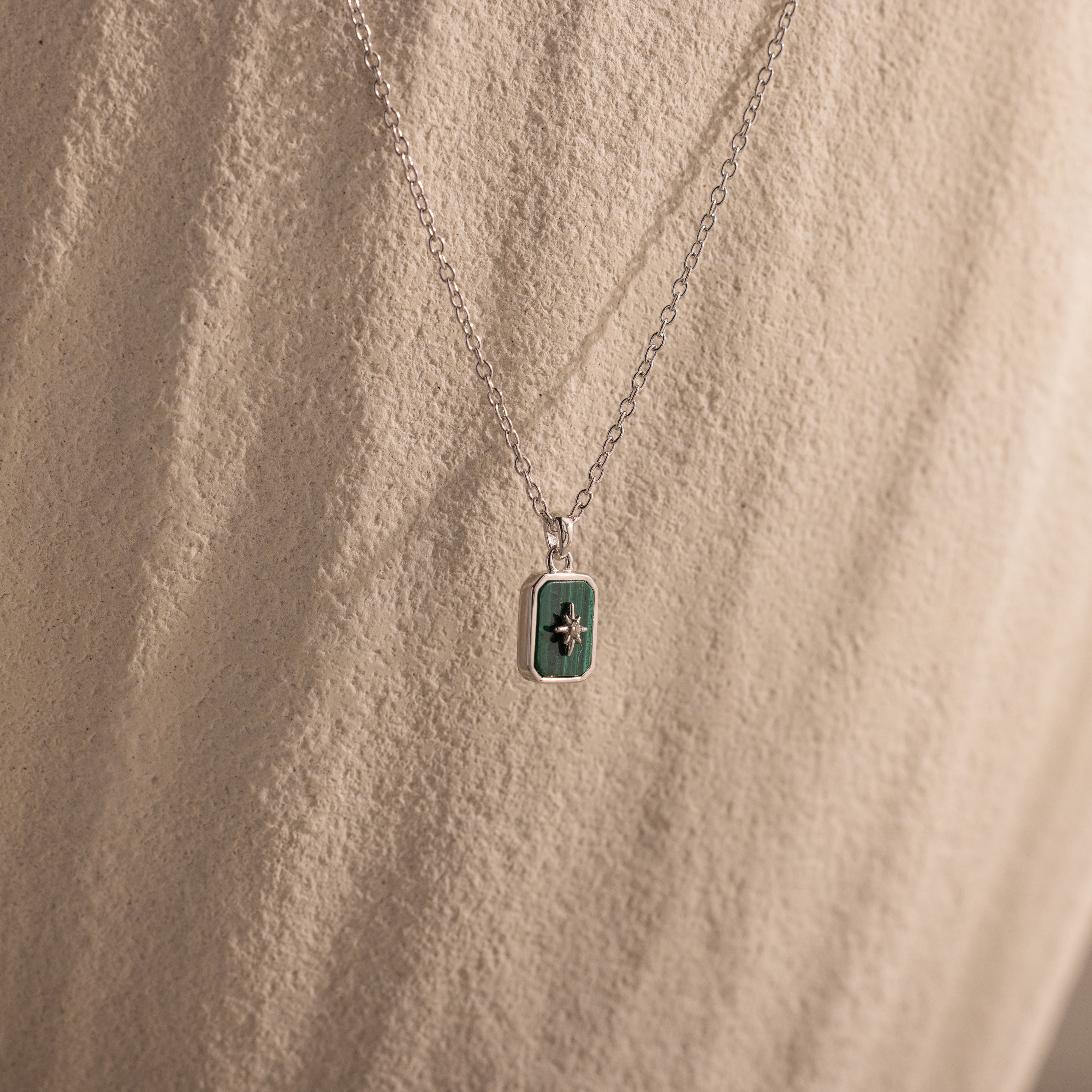 North Star Gemstone Necklace in Sterling Silver featuring a malachite rectangular pendant with a small star design, shown on neutral fabric.