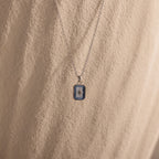 North Star Aquamarine Necklace with a small rectangular pendant and a North Star design, accented by aquamarine stones, set against a textured beige background.