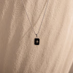 North Star Gemstone Necklace featuring a black rectangular pendant with a small star design, displayed on a textured beige background.