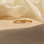 A set of crystal stacking rings in 18K gold displayed on a light surface with a soft fabric backdrop—an elegant jewelry accent to suit any style.