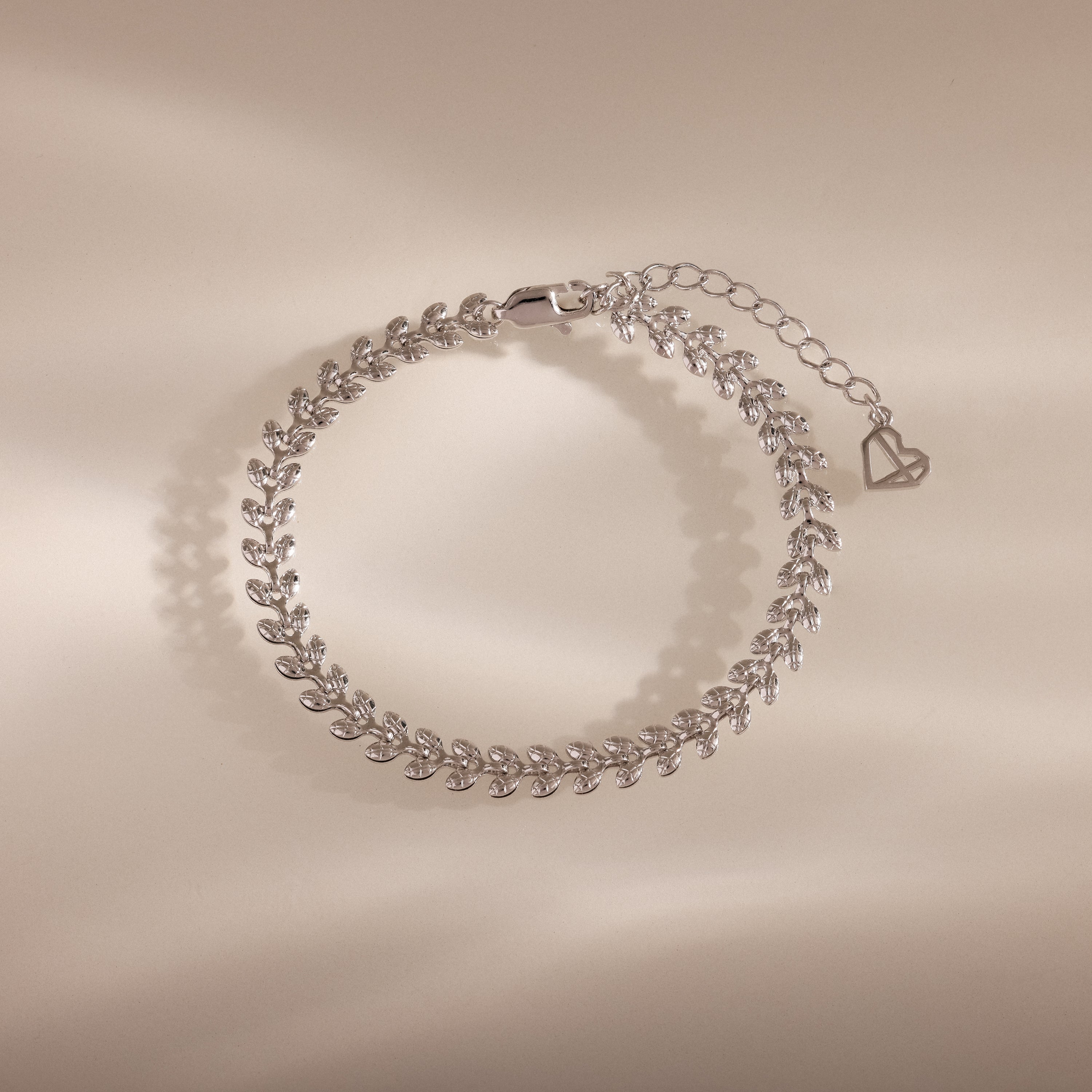 The Fishtail Chain Bracelet in Silver features an elegant leaf pattern with adjustable interwoven links and a heart-shaped charm—perfect as a stylish gift for any occasion.