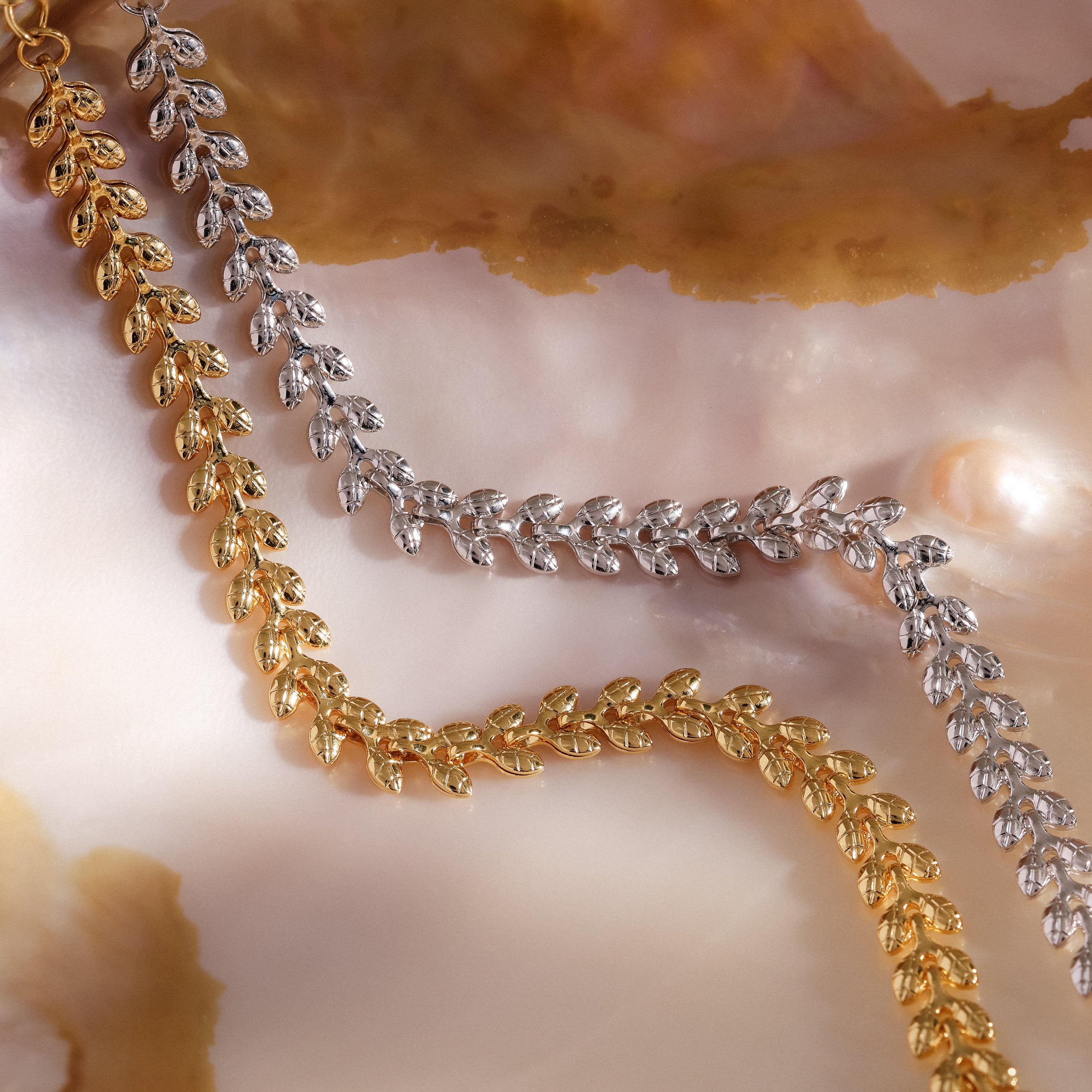 The Fishtail Chain Bracelet, featuring intricate craftsmanship and a cascading texture, is displayed on a marbled, pearlescent background.
