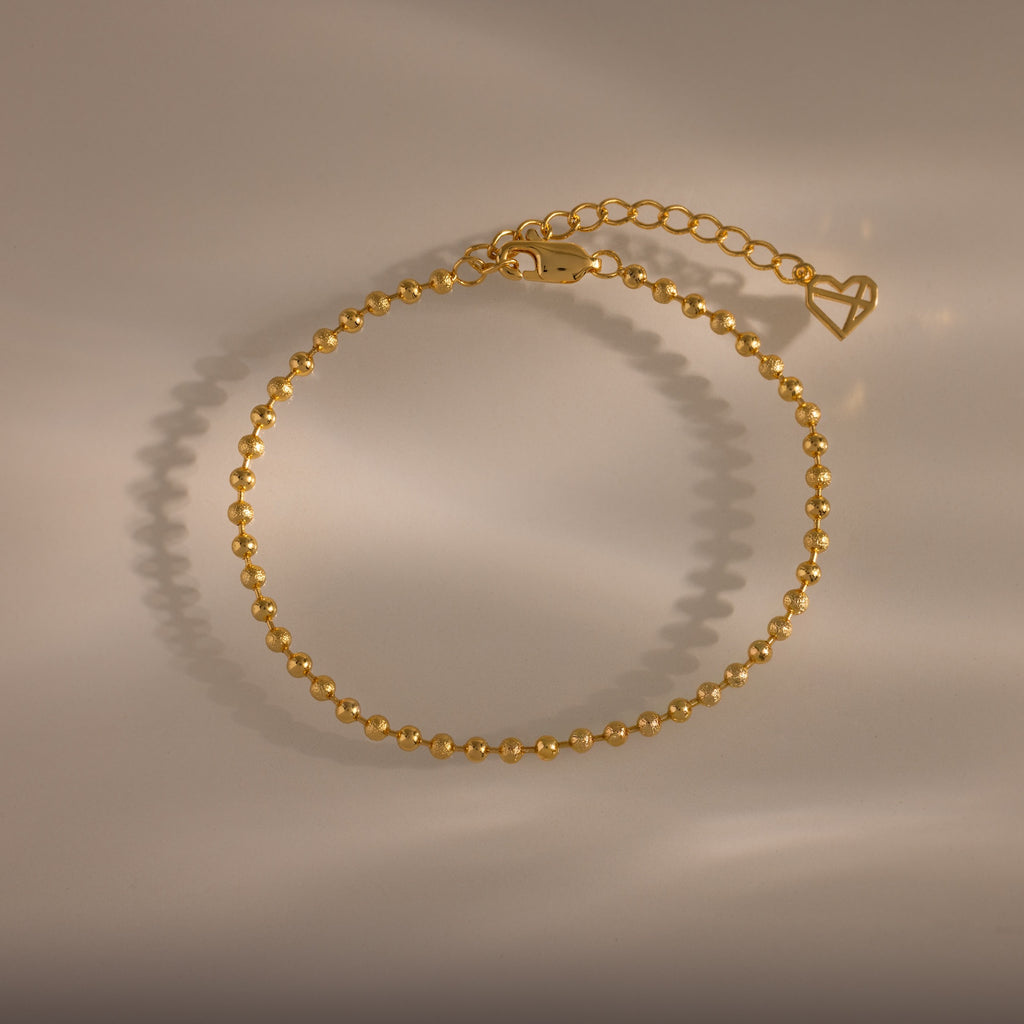 Dune Beaded Bracelet: gold polished beads with adjustable clasp and heart charm, ideal for layered looks—shown on a neutral background with soft shadows.