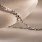 Close-up of the Dune Beaded Bracelet with polished silver beads resting on a smooth, beige stone surface.