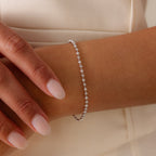 A hand with manicured nails wears the Dune Beaded Bracelet in Silver, featuring polished beads and small stones on the wrist.