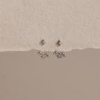 Starburst Cluster Ear Jackets in Sterling Silver, inspired by celestial jewelry, displayed on a textured cream and beige background.