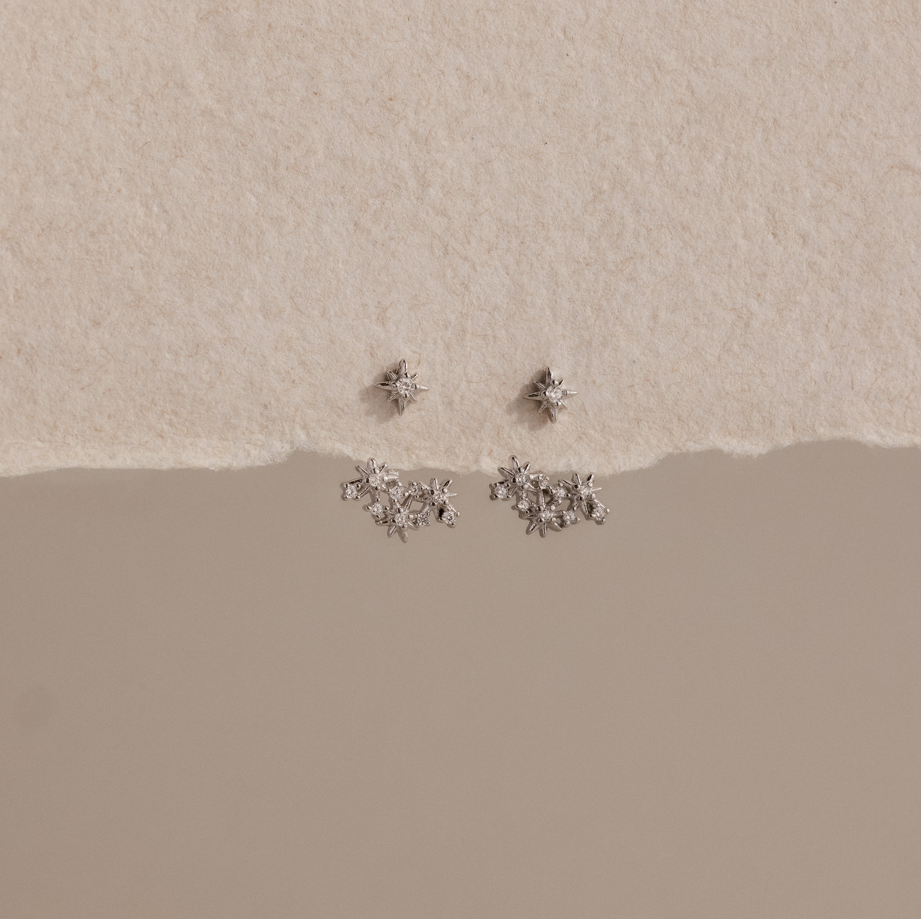 Starburst Cluster Ear Jackets in Sterling Silver, inspired by celestial jewelry, displayed on a textured cream and beige background.