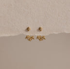 The Starburst Cluster Ear Jackets are displayed on a textured beige background, making them a perfect choice for fans of celestial jewelry.