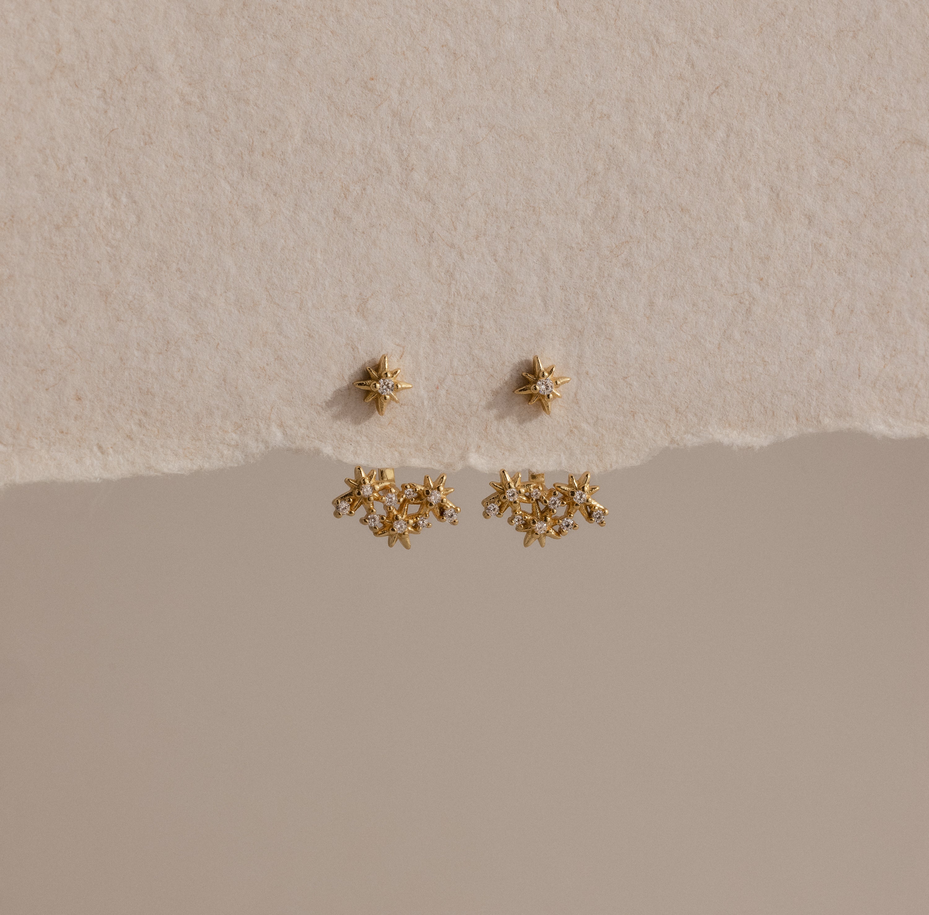 The Starburst Cluster Ear Jackets are displayed on a textured beige background, making them a perfect choice for fans of celestial jewelry.