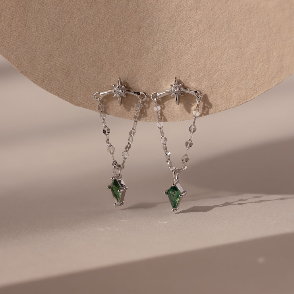 Agate Star Chain Earrings in Sterling Silver feature star-shaped studs, chain drops, and green agate gemstone pendants for a celestial look that dazzles against any neutral backdrop.