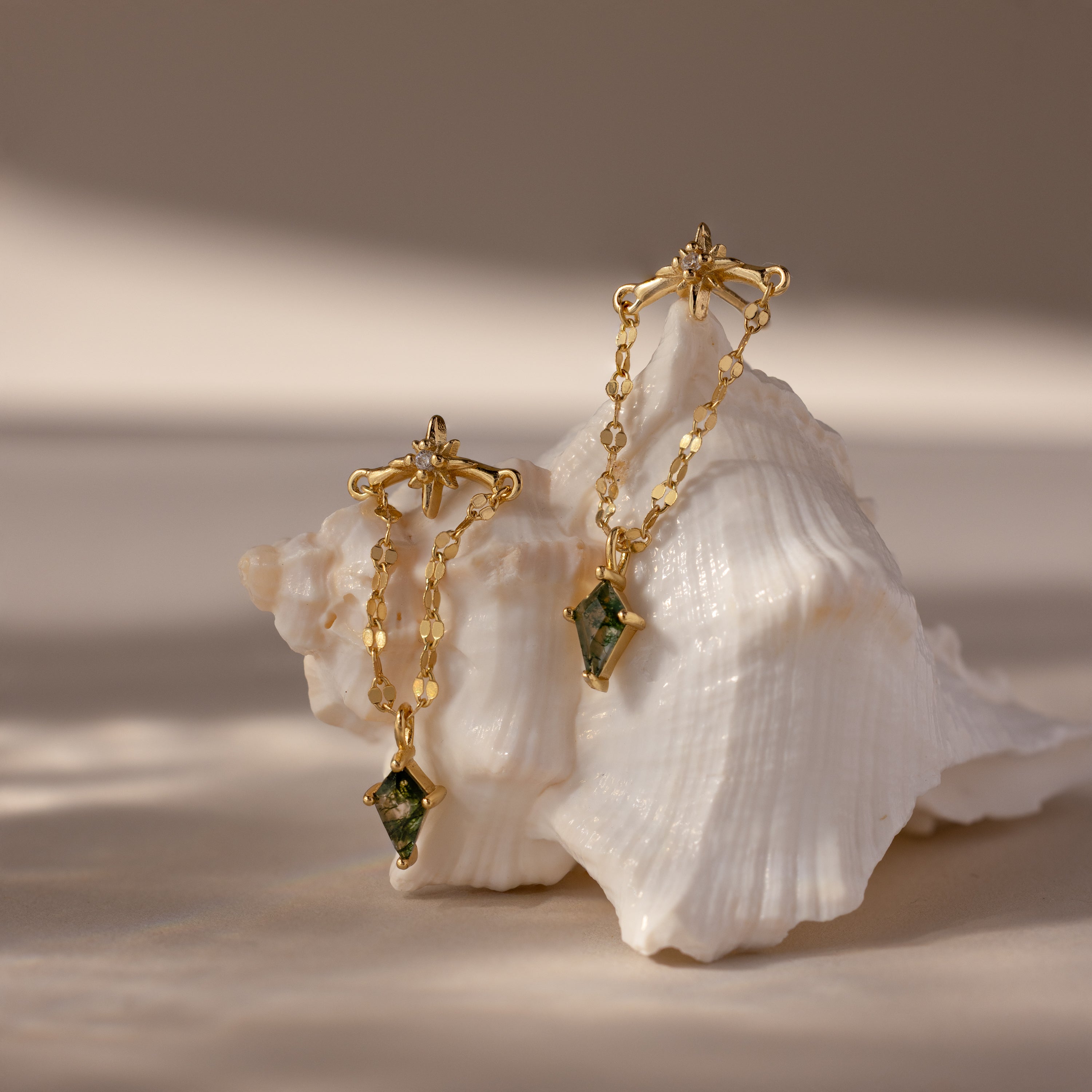 Agate Star Chain Earrings in 18K Gold with green agate gemstone drops, displayed on a white seashell against a neutral background.