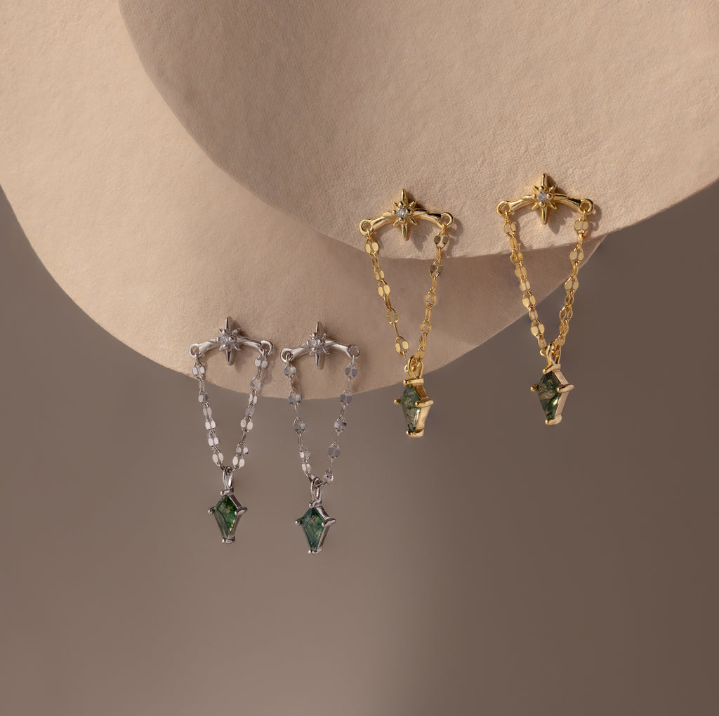Two pairs of decorative earrings—one silver, one gold—feature green agate accents and chain details, inspired by the Agate Star Chain Earrings.